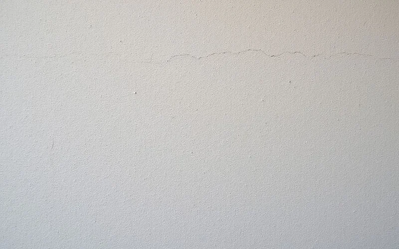 Close up of textured stucco wall with hairline cracks before paint prep on a Phoenix home